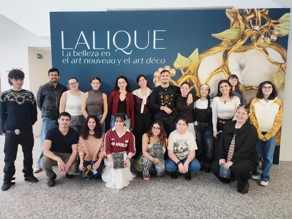 Alumnado de la Escuela Técnica de Joyería del Atlántico ante el cartel de la exposición “Lalique. La belleza en el art nouveau y el art déco” en la Fundación Barrié