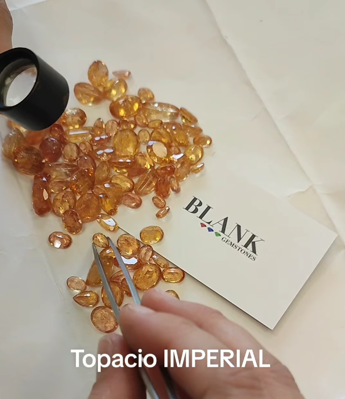 Topacios imperiales tallados examinados con lupa y pinzas durante la masterclass de Blank Gemstones